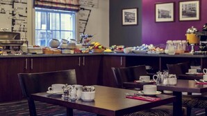 Ein Frühstücksbuffet mit verschiedenen Speisen, einer Kaffeemaschine und Sitzmöglichkeiten.