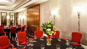 Ein Konferenzraum mit roten Stühlen, einem schwarzen Tisch und einer Blumenkomposition.