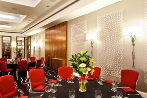 A conference room with red chairs, a black table, and a floral centerpiece. - Nottingham City Centre Deluxe Quad Room (Nottingham)
