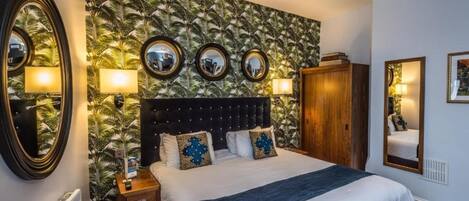 Una habitación de hotel con cama, mesitas de noche, un espejo y un armario.