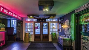 Eine Hotelhalle mit einer Neonreklame, einer stadtmotierten Tür und einem Starbucks-Logo.