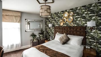 A bedroom with a large bed, a mirror, a wall clock, and a tropical wallpaper.
