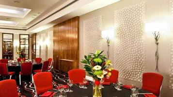 A conference room with red chairs, a black table, and a floral centerpiece.