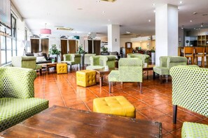 A spacious lobby with multiple seating areas, including green patterned chairs and yellow ottomans, and a visible kitchen area in the background. - Sheffield Metropolitan by Belvilla - Standard King Room (Sheffield)