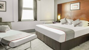 Et hotelværelse med to senge, et stort vindue, et træhovedgærde og et indrammet kunstværk på væggen.