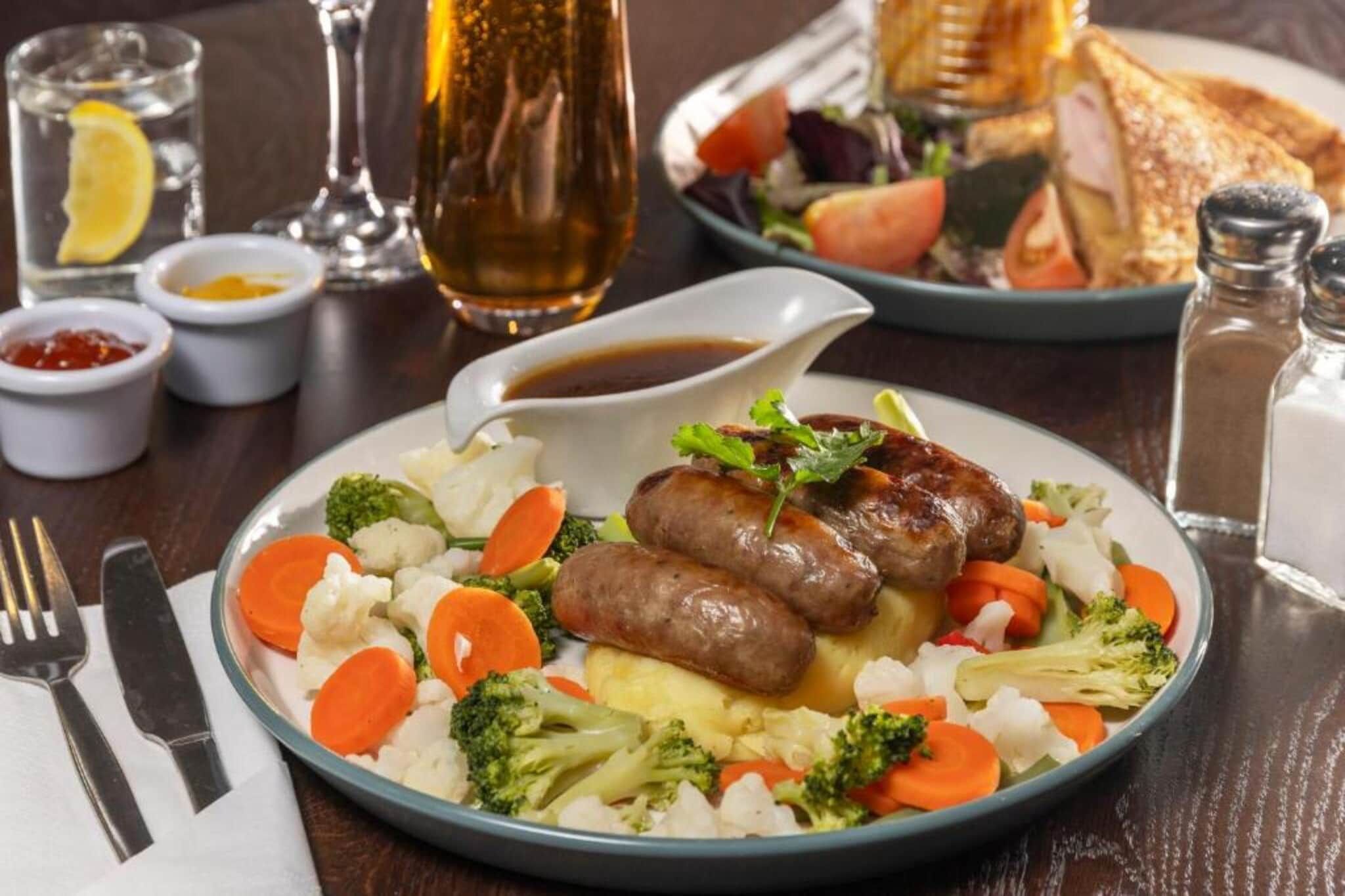 Ein Teller mit Würstchen, Gemüse und Soße.