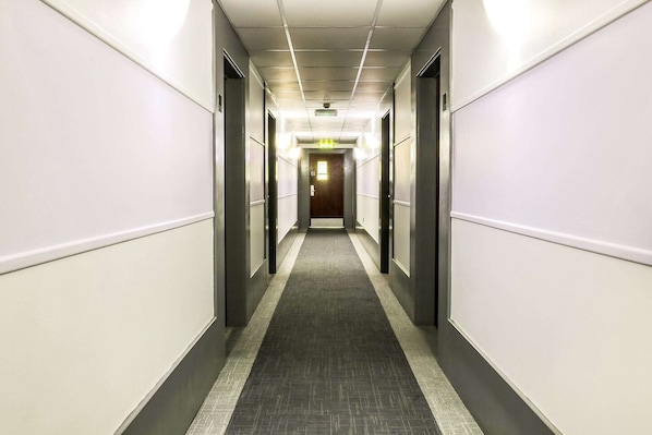 A long, narrow hallway with a carpeted floor, doors on both sides, and a light at the end. - Sheffield Metropolitan by Belvilla - Standard Triple Room (Sheffield)