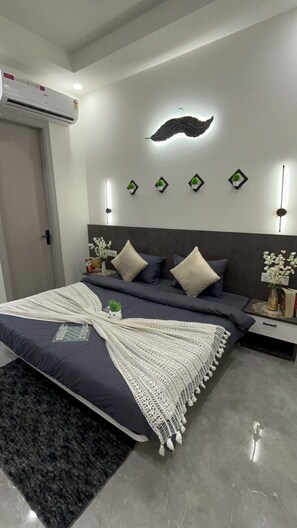 Ein Schlafzimmer mit einem Bett, Nachttischen, einer wandmontierten Klimaanlage und dekorativer Wandbeleuchtung.