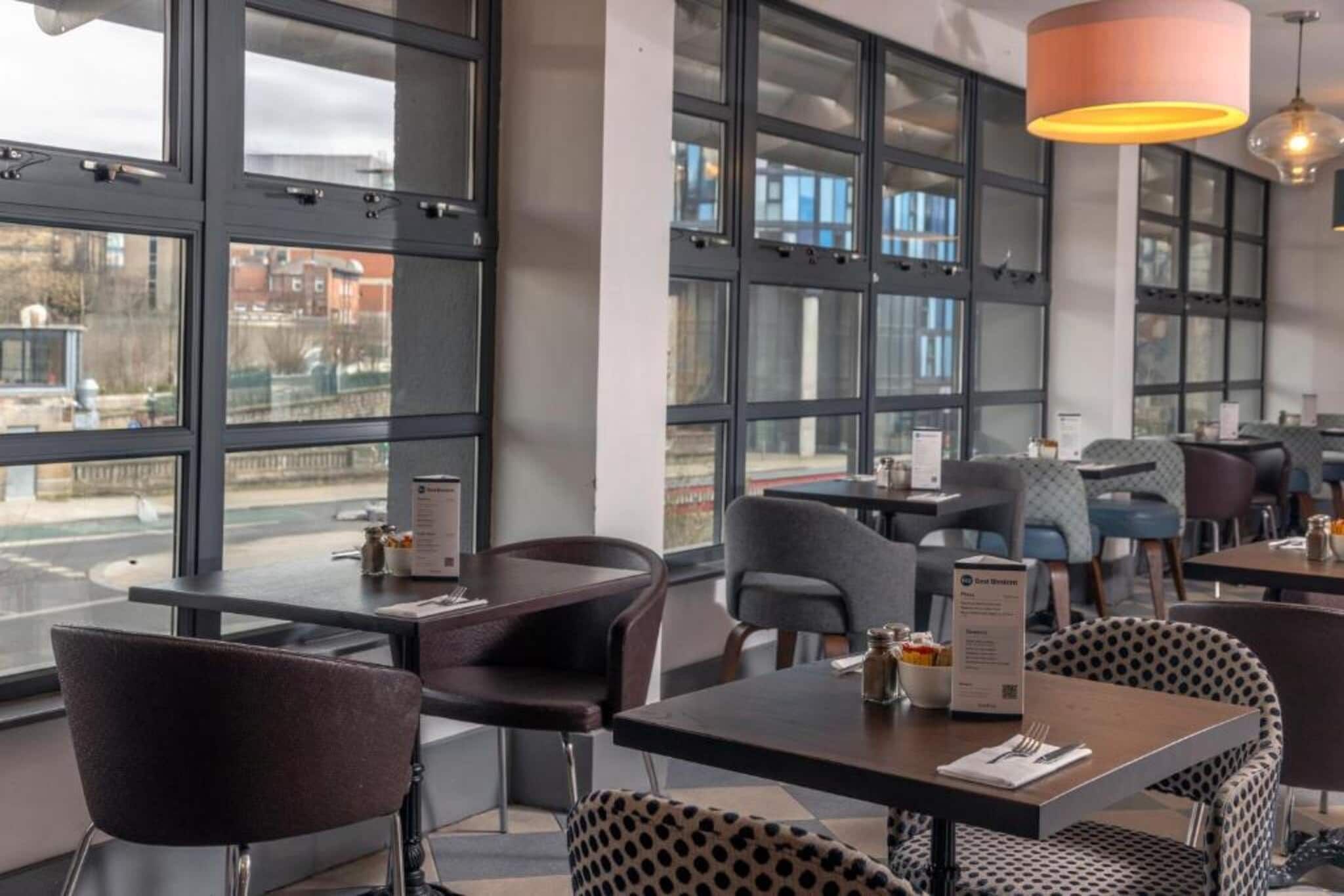 Un intérieur de restaurant moderne, avec de grandes fenêtres, des tables et des chaises.