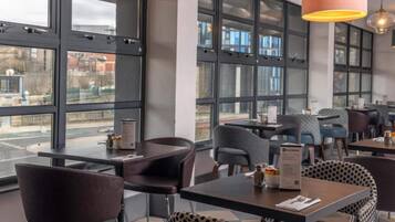 Un intérieur de restaurant moderne, avec de grandes fenêtres, des tables et des chaises.