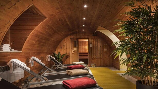 Una sala de spa de fusta amb sauna, tovalloles i una planta en test.