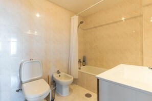 A bathroom with a toilet, bidet, bathtub, and a sink. - Aurora Atlantic Apartment by Atlantic Holiday (Caniço)