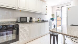 A kitchen with white cabinets, a microwave, a coffee maker, and a washing machine. - Aurora Atlantic Apartment by Atlantic Holiday (Caniço)