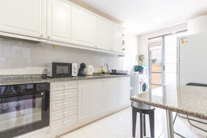 A kitchen with white cabinets, a microwave, a coffee maker, and a washing machine. - Aurora Atlantic Apartment by Atlantic Holiday (Caniço)