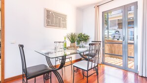 A dining area with a glass table, black chairs, a plant, and a bottle of olive oil. - Aurora Atlantic Apartment by Atlantic Holiday (Caniço)