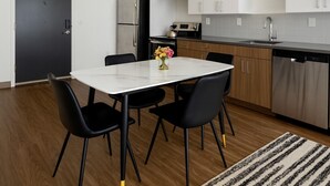 A modern kitchen with a white countertop, stainless steel appliances, and black chairs around a white table. - Upscale 2BR Apt | Rooftop Deck + Fitness U14 (Birmingham)