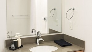 A bathroom with a large mirror, a sink, a towel rack, and a cabinet. - Upscale 2BR Apt | Rooftop Deck + Fitness U14 (Birmingham)