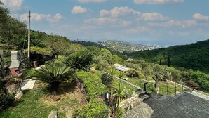 A hillside with a stone staircase leading down, surrounded by lush greenery and a distant view of a town. - Stunning home in San Lorenzo della Cost with house a panoramic view (San Lorenzo della Cost)