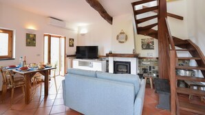 A living room with a sofa, TV, fireplace, dining table with chairs, and a staircase. - Stunning home in San Lorenzo della Cost with house a panoramic view (San Lorenzo della Cost)
