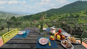 A table set outdoors with plates of food, a vase with flowers, and a scenic mountain view. - Stunning home in San Lorenzo della Cost with house a panoramic view (San Lorenzo della Cost)