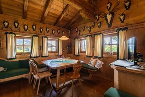 A rustic wooden interior with a dining table, benches, and a sofa.