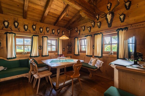 A rustic wooden interior with a dining table, benches, and a sofa.