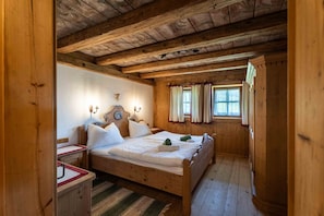 A wooden cabin bedroom with a bed, nightstands, and a window with curtains.
