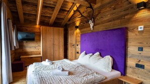A wooden cabin-style room with a bed, a television, and a mounted deer skull. - Panorama Alm Chalet - Jägersruh Zwei, Ski-in / out & mountain view (Saalbach)
