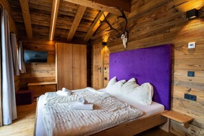 Une pièce de style cabane en bois, avec un lit, un téléviseur et un crâne de cerf accroché au mur.
