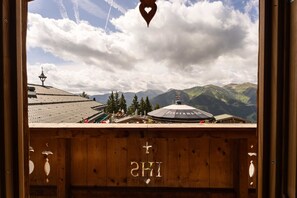 A wooden cabin with a view of mountains and a church steeple.