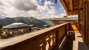 A wooden balcony overlooking a mountain landscape with a restaurant and a mountain hut. - Panorama Alm Chalet - Jägersruh Zwei, Ski-in / out & mountain view (Saalbach)