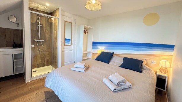 Ein Schlafzimmer mit Bett, Dusche, Kleiderschrank und Spiegel.