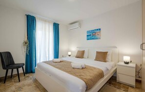 A hotel room with a bed, a chair, a bedside table, a nightstand, and a wall-mounted air conditioner. - 2 bedroom awesome apartment in Kotor (Kotor)
