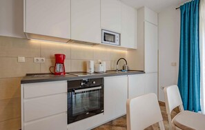 A compact kitchenette with a Bosch oven, a microwave, a red coffee maker, and a sink. - Cozy apartment in Kotor with WiFi (Kotor)