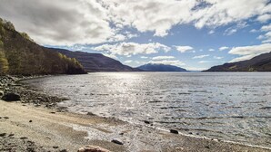 A lake with a rocky shoreline and mountains in the background.