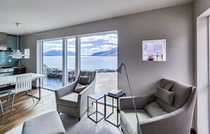 A modern living room with a large sliding glass door leading to a balcony with a view of the sea and mountains. - Lovely home in Sandeid with WiFi (Sandeid)