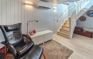 Een modern interieur met een leren fauteuil, een wit bureau, een trap en uitzicht op de omgeving.