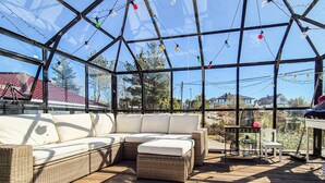 Ein überdachter Patio mit Korbmöbeln und Lichterketten.
