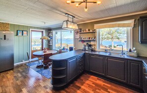 Una cocina con una isla grande, armarios oscuros y vistas al exterior.