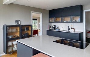 A modern kitchen with a central island, dark cabinetry, and a glass-fronted display cabinet. - Stunning home in ålesund with house sea view (Ålesund)