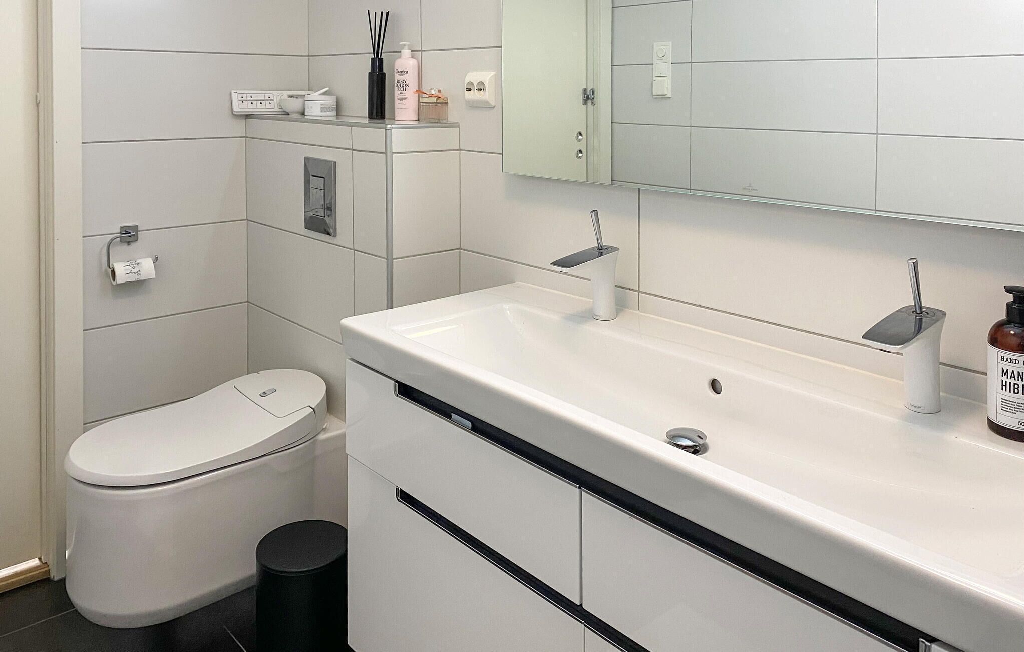 A modern bathroom with a toilet, sink, and mirror.