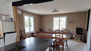 A kitchen with a refrigerator, a dining table with chairs, and a television. - House 5 mn walk from the center of aiguillon (L'Aiguillon-la-Presqu'île)