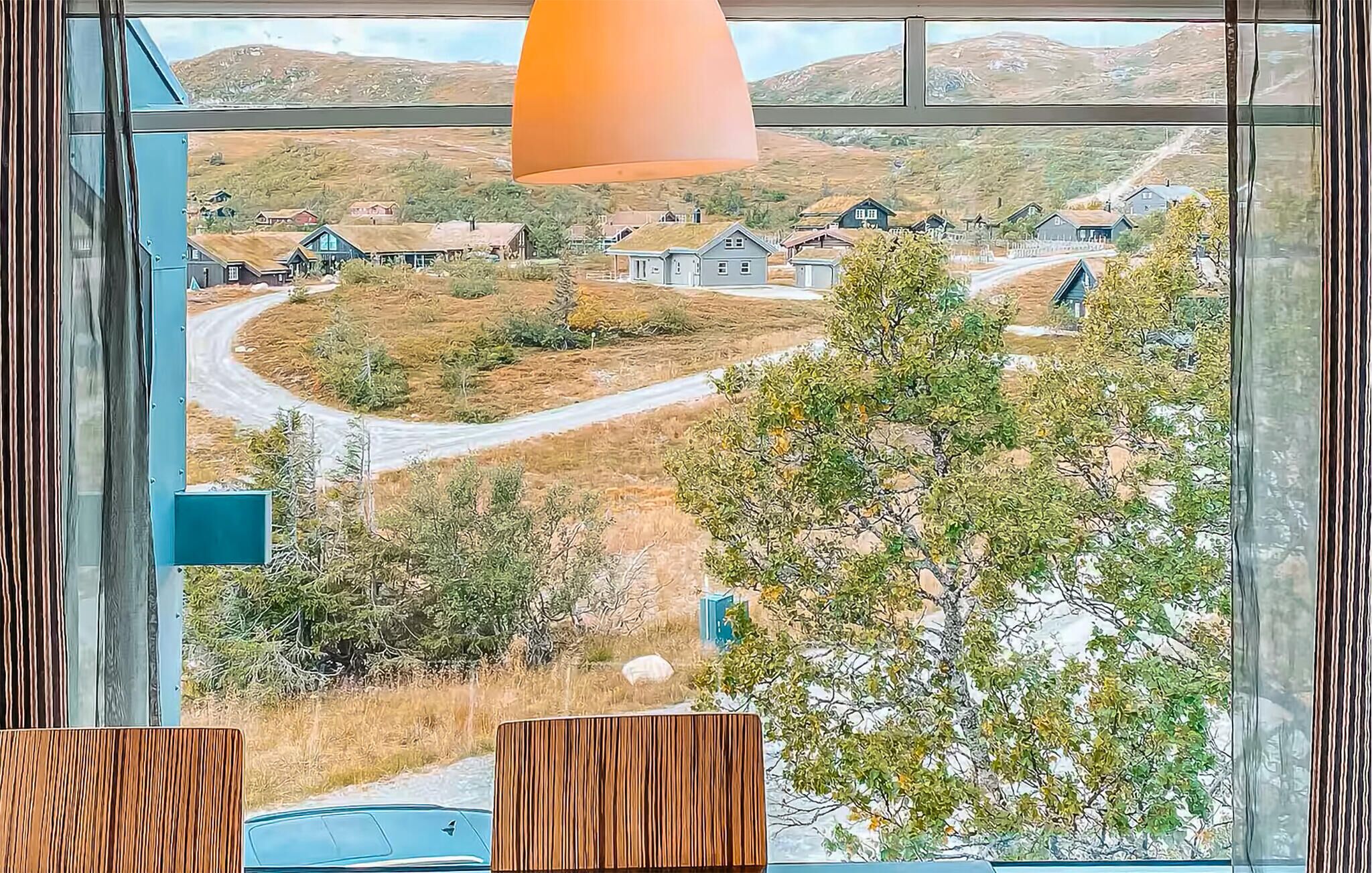 A room with a large window overlooking a rural landscape with houses and a road.