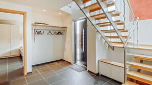 Een modern interieur met een spiltrap, een kapstok en een radiator.