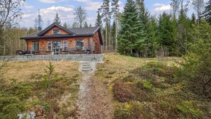 A log cabin with a stone pathway leading to the entrance, surrounded by dense forest. - Amazing home in ørje with WiFi (Ørje)