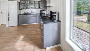 A modern kitchen with grey cabinets, a stainless steel coffee maker, and a window with a view of greenery. - Amazing home in ørje with WiFi (Ørje)