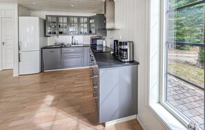 A modern kitchen with grey cabinets, a stainless steel coffee maker, and a window with a view of greenery. - Amazing home in ørje with WiFi (Ørje)