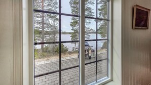 A window with a grid pattern, a view of a lake, and a parked vehicle outside. - Amazing home in ørje with WiFi (Ørje)