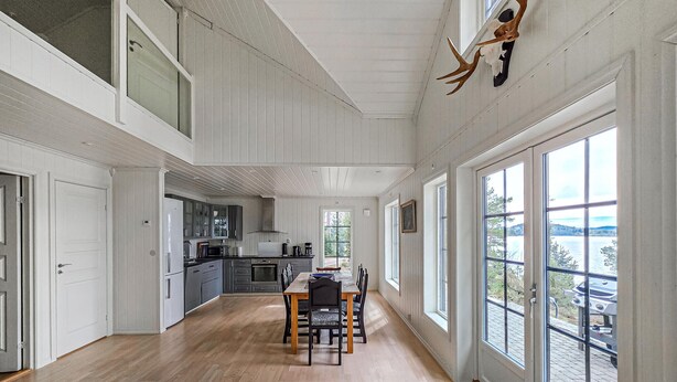 A spacious kitchen with modern appliances, a dining area with a wooden table, and large windows offering views of the outdoors. - Amazing home in ørje with WiFi (Ørje)