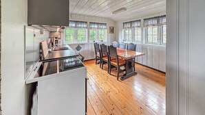 A kitchen with a refrigerator, stove, and dining table with chairs. - Amazing home in ørje with house sea view (Ørje)